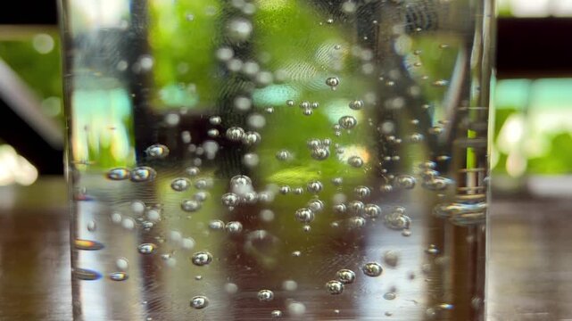 Slow motion of air bubbles of sprite lemonade in glass on wooden table, Mahe, Seychelles 25fps