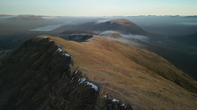 Glen Coe and Rannoch Moor, Scottish Highlands - aerial over the mountains in winter with sun and low cloud on hills