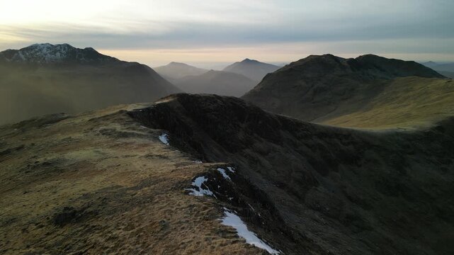Glen Coe, Scottish Highlands - aerial over the mountains in winter with reveal of Loch Achtriochtan in glen below