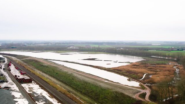 Aerial view of a polder with a large pond next to industry. Drone shot