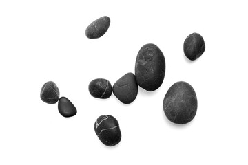 Smooth black pebbles scattered on a white background, showcasing various shapes and textures, ideal for natural decor and design concepts with copy space
