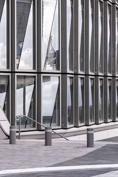 Modern architecture with glass facade reflection columns and pavement bollards showing clean geometry and empty corporate exterior with copy space