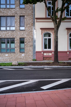Quiet daylight street with empty sidewalk crosswalk and brick facade windows plus tree in urban neighborhood scene with copy space