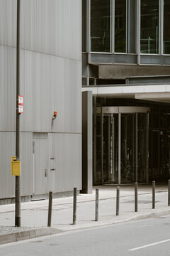Modern building entrance with glass doors concrete sidewalk and bollards in an empty urban setting showing clean lines and corporate copy space