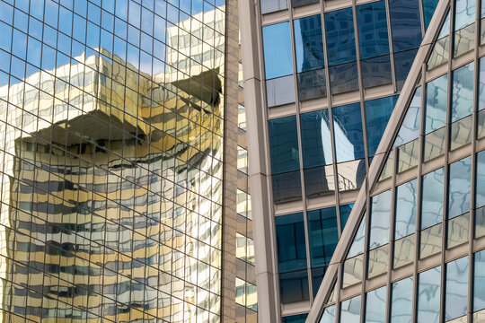 Modern corporate urban architecture building facade with glass reflection and diagonal structure creating sleek office skyline background texture