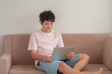 Young man sitting on the couch with a laptop, online communication in a teenager chat concept