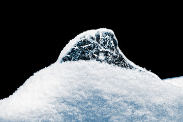 Ice under the snow on a black background. Resembles a shark fin.