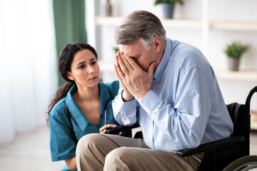 A woman with dark hair listens to a man with gray hair as he expresses his feelings while seated in...