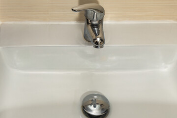 Fototapeta premium Water leaking from the tap into the sink, dripping clean water, data leak, bathroom faucet