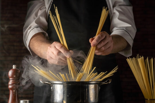 Chef cooks pasta in a pot while holding uncooked spaghetti in a kitchen during dinner preparation