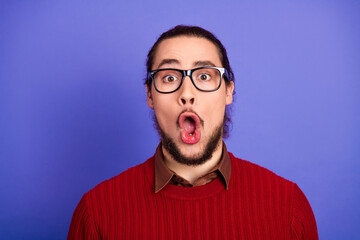 Surprised handsome man with glasses wearing a red sweater stands against a violet background in a casual stylish portrait perfect for lifestyle fashion education and advertising campaigns