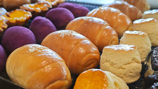 Close-up of golden brown Shio Pan (Japanese salt bread) with shiny crust and a sprinkle of salt, displayed in a bakery setting