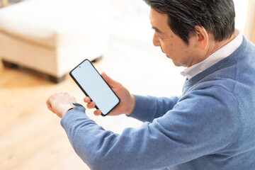 携帯を持ちスマートウォッチを見る男性