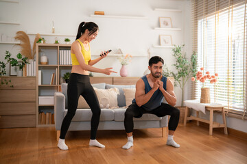 Obraz premium Woman coaching man during squat exercise at home