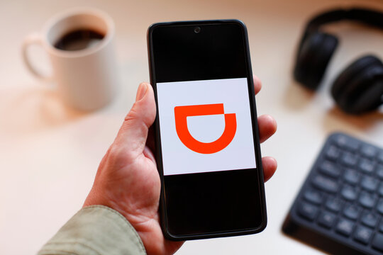 VALENCIA, SPAIN &ndash; 01-27, 2026: DiDi APP On Mobile Phone With Brand Logo Displayed, Coffee, Keyboard And Headphones In Workspace
