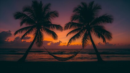 Obraz premium Silhouette of two palm trees with a hammock at sunset