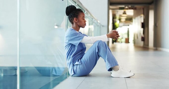 Black woman, nurse and headache in grief, burnout or mistake on floor in hospital. Mental health, sad physician and medical person with healthcare anxiety for stress, loss or failed surgery at clinic