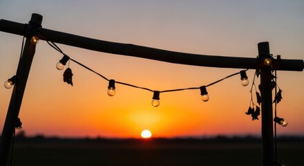 Wooden structure with string lights silhouetted against a sunset