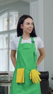 Close up of good-looking in high spirits responsible 30-aged woman which standing in the middle of contemporary kitchen-studio,ties green apron while begining to clean up this room