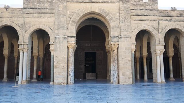 The Great Mosque of Kairouan in Kairouan, Tunisia, with iconic minaret, stone arcades, and open prayer space under a clear blue sky, symbolizing Islamic heritage and architecture