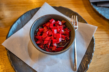Beetroot salad in bowl on black plate, napkin, fork.