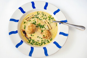 Cheese soup with bacon dumpling in striped plate on white.