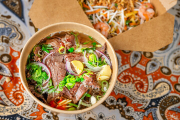 Vietnamese soup Pho Bo and box with mango salad.