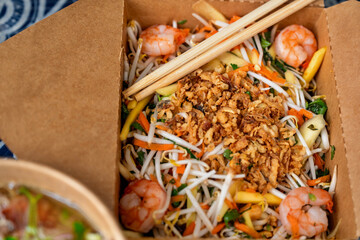 Box with mango salad and chopstick and bowl with soup Pho Bo