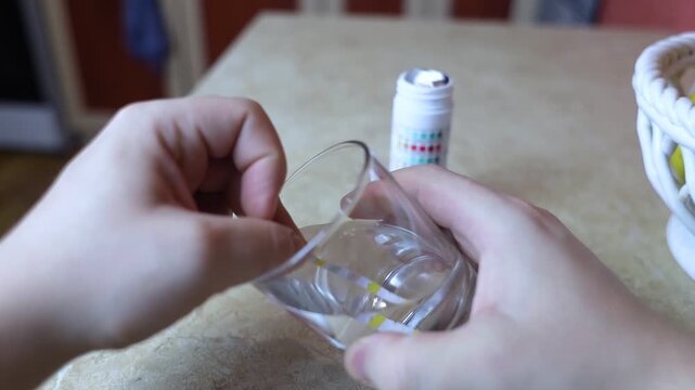 A man in the kitchen tests tap water quality with a test strip. Home testing for drinking water safety, pH, chlorine, and chemical contaminants.
