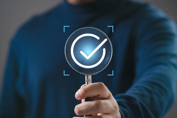 Magnifying glass highlighting a check mark icon, representing verification, approval, quality control, successful validation, compliance process, and confirmation of completed tasks. © Bordinthorn