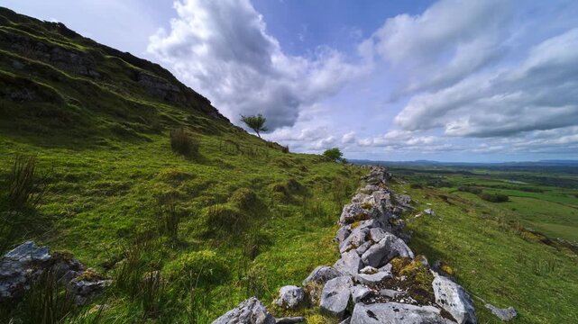 Panorama motion timelapse of rural landscape with rocks and trees in the foreground and hills in the distance during sunny cloudy day viewed from Carrowkeel in county Sligo in Ireland.