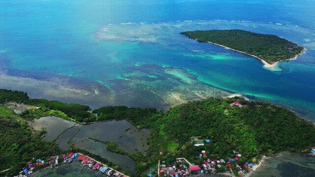 Slow side aerial showing Luan and Magalawa Islands, turquoise waters, white sand beaches, and tropical vegetation.