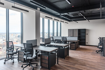Open office interior with modern workstations and wood accents on floor. Panoramic view of open plan office with city skyline in background