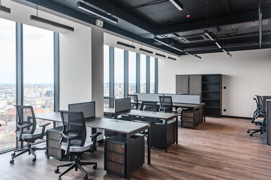 Open office interior with modern workstations and wood accents on floor. Panoramic view of open plan office with city skyline in background