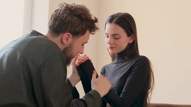 Intimate moment between a loving young couple sitting opposite each other and tenderly holding hands, showing their deep affection, emotional connection, care, and support for one another