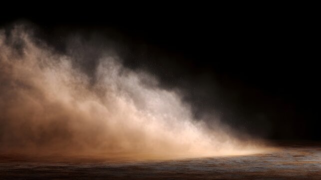 A dramatic cloud of light brown dust swirls and scatters against a deep dark background illuminated by a bright light source