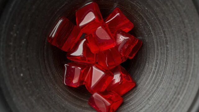 Vibrating speaker driver moving red translucent cubes in cone on tabletop, changing highlights