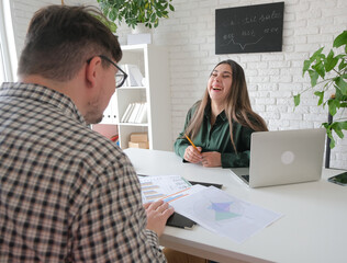 man and woman working in small office, woman laughing