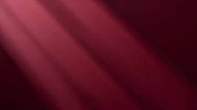 Directional light shifting across maroon fabric with diagonal bands in studio, suggesting motion