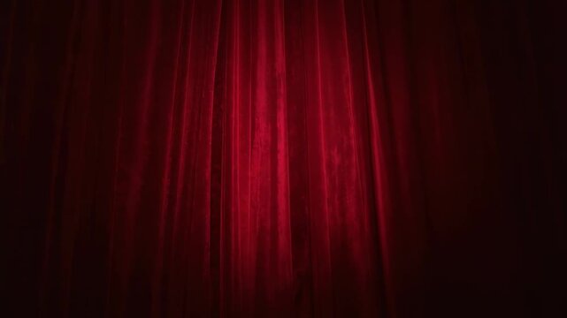Spotlight turning on and shifting across deep-red velvet curtain at theater proscenium for show