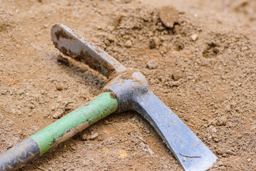 Close up of pickaxe head lying on brown soil The Concept of Hard Work