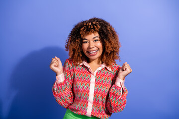 Young chic female model smiles brightly in colorful zigzag blouse against blue background