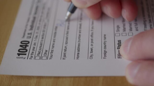 Man Filling In The Tax Form 1040 for 2025 Year. Person Calculates of Planning Budgets Yearly Personal Finance and Fills up US Tax Form 1040 For 2025 Year. Signing 1040 Income Tax Return For 2025 Year.