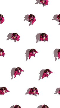 Video ad. Top view pattern of woman in pink winter outfit on white background. Concept of apparel styling showcase, seasonal clothing visuals, and creative fashion layouts for marketing use.