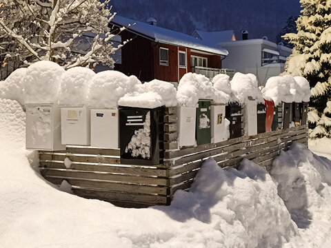 Briefk&auml;sten mit wei&szlig;en M&uuml;tzen und tief verschneite Stra&szlig;e im Winter zur Nacht