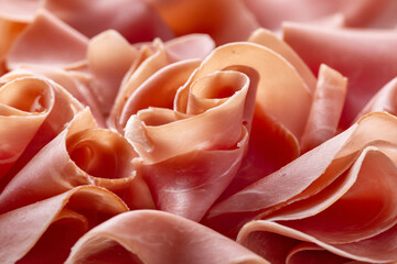 A close-up view of thinly sliced pink ham arranged in rose-like curls