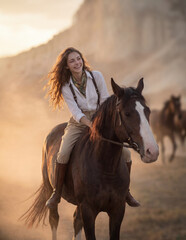 Obraz premium A young woman with a brown horse in a scenic valley with mountains background