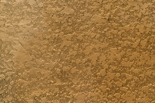 Gold tan stucco wall texture background with rough knockdown plaster surface for architectural design interior home decor or construction material close up