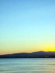 Fototapeta premium Peaceful sunset over mountains with calm sea in foreground