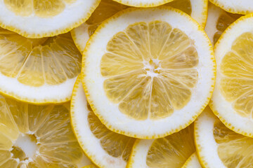 Slices of lemon laid out in a pattern showing the yellow fruit with a bright appearance in warm light